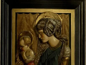 Painted terracotta relief of Madonna and Child with halos, the woman in blue and gold holding a child in red against a gilt background.