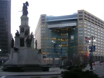 Michigan Soldiers\' and Sailors\' Monument in a city plaza with a modern glass-and-stone building behind it.