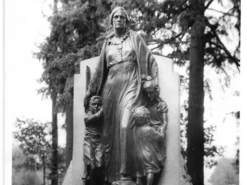 Pioneer Mother Memorial statue of a woman with three youths holding her garments, set on a rocky base with a fountain below.