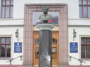 Weathered bronze Pushkin bust on a tall dark stone pedestal with flower boxes at the base