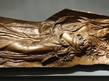 Bronze figure from the Shaw Memorial with flowing drapery, leaves at the chest, and a rectangular panel behind the head.