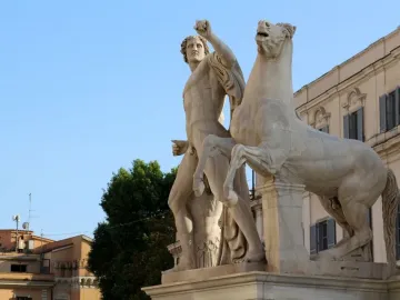 White marble Horse Tamers sculpture with a muscular figure beside a rearing horse on a stone pedestal.