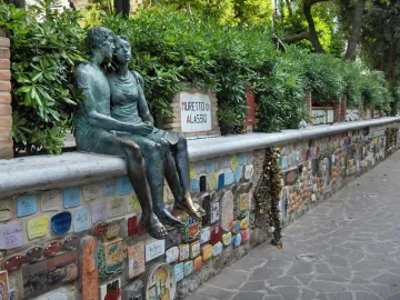 The Muretto of Alassio, a stone wall covered with colorful signed ceramic tiles and a bronze couple sculpture.