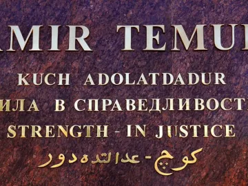 Close-up of the Amir Temur inscription with gold lettering on a reddish-brown stone surface.