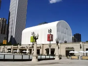 Cloud Gate covered by a large white tent in a city plaza.