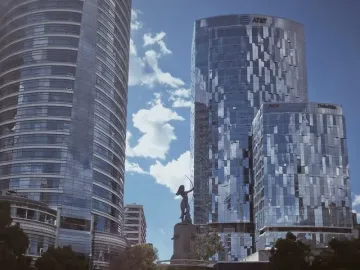 Diana the Huntress Fountain with a figure drawing a bow against a clear sky and city skyscrapers.