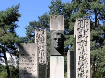 Julius Fučík Memorial with five stone pillars, including a central pillar with a metal bust and carved inscriptions.
