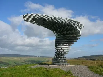 The Singing Ringing Tree sculpture on a grassy hill above a wide green valley.
