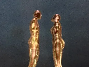 Ali and Nino sculpture with two golden segmented figures facing each other at night