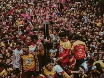 Black Nazarene statue carried through a tightly packed crowd of devotees reaching out to touch it