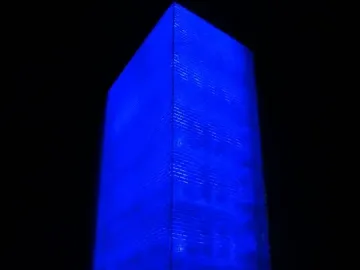 A tall, rectangular blue-lit structure of Crown Fountain glows at night.