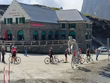 Géant du Tourmalet statue of a cyclist beside a mountain restaurant, with cyclists and bikes in the foreground