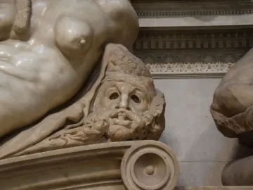 Detail of Michelangelo\'s Night showing a reclining female figure and a grimacing bearded face below her.