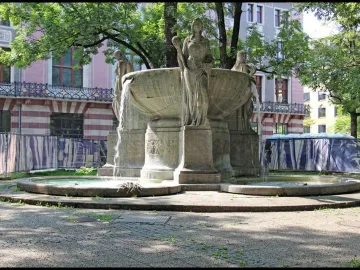 Nornenbrunnen stone fountain with three draped female figures and cascading water in Munich.