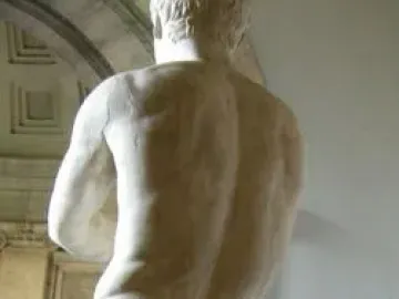 Apoxyomenos, a marble nude male statue seen from behind in a museum setting.