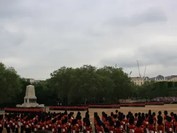 Guards Memorial with a parade of guards in red uniforms and bearskin hats standing in the courtyard.