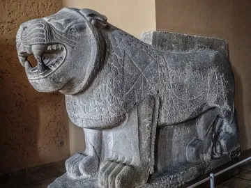 Weathered stone Sam\'al lion sculpture with an open mouth and carved mane