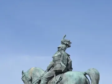 Victor Emmanuel II equestrian statue in bronze atop a stone pedestal against a blue sky.