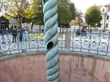 The Serpent Column stands in a stone-paved enclosure with a broken top and greenish-bronze patina.