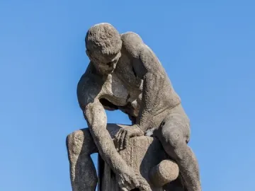 Tauzieher, a weathered stone sculpture of a muscular man pulling a thick rope around a stone post.