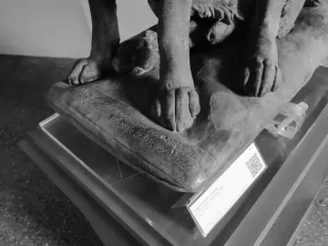Lower part of Cane Tago, showing the dog sculpture’s four paws on a carved base.