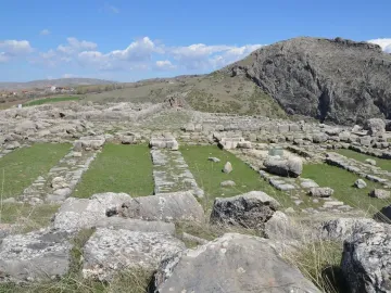Hattusa green stone block standing among ancient grey stone ruins and patches of grass