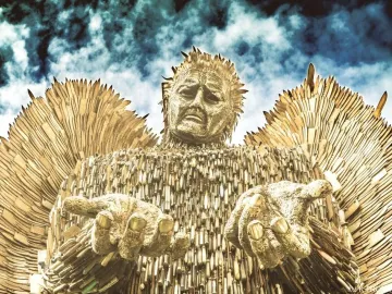 The Knife Angel sculpture shown from below against a cloudy sky, with outstretched hands and wing-like forms made from blades and knife handles.