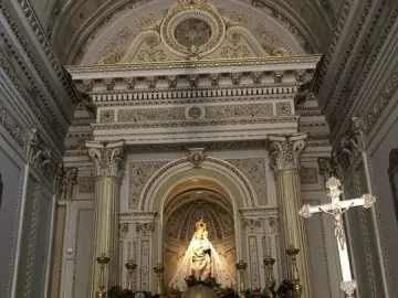 Crowned statue of Madonna dell\'Udienza in an ornate church niche above a marble altar.
