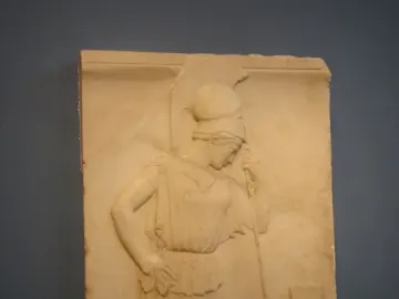 Mourning Athena relief showing a helmeted female figure in profile, leaning on a staff beside a rectangular stele.