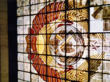 Stained glass window with the Soviet emblem, including a hammer and sickle, wheat sheaves, and a red star.