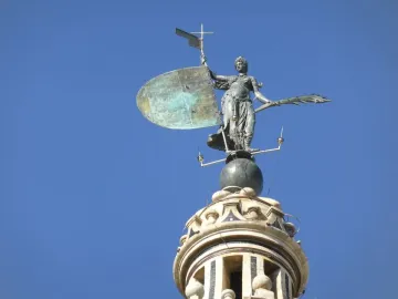 The Giraldillo sculpture of a robed woman holding a shield and palm frond against a blue sky.