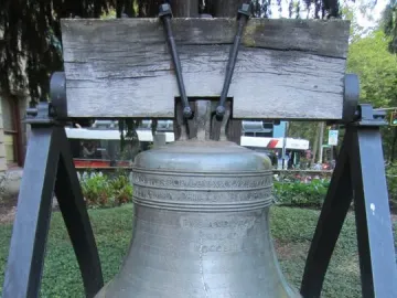 The Liberty Bell displayed outdoors on a wooden beam with metal supports and a visible crack.