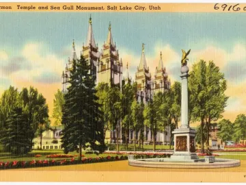 Seagull Monument with a golden bird sculpture on top of a tall white base in a landscaped park setting.