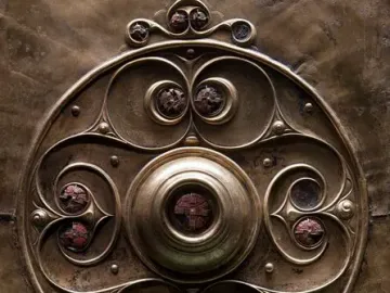 Close-up of the Battersea Shield showing a central boss, swirling bronze patterns, and circular inlays.