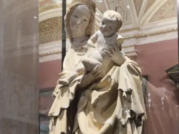 Krumlov Madonna statue of a mother holding a child, shown in a museum display case.