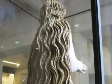 Back and right side of the Mary Magdalene statue, with long wavy hair covering the carved figure behind glass.