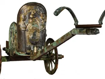 The Monteleone Chariot with ornate bronze relief figures and a central mask-like design on the front panel.
