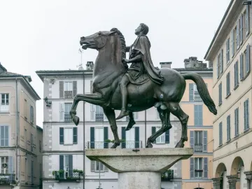 The Regisole equestrian statue stands on a stone pedestal in a city square in Pavia.