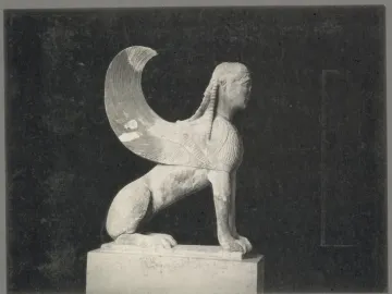 Weathered stone Sphinx of Naxos sculpture in profile with a large wing, shown on a pedestal.