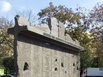 Monument to the Victims of the Wola Massacre with a rough-hewn granite face covered in names and dark indentations.