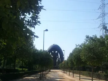 Birth of a New Man sculpture in the distance at the end of a dirt path lined with trees.