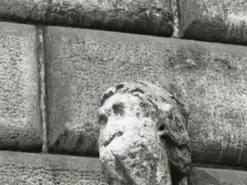 Pasquino, a severely weathered stone statue with a missing left arm, shown against rough stone blocks.