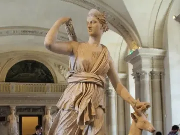 Diana of Versailles statue with a deer beside her in a museum gallery