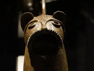Close-up of the Lion of Monzon sculpture showing its gaping mouth and textured metal head.