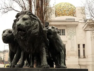 Marc Anton Group sculpture with lions pulling a chariot in front of a white building with a golden dome.