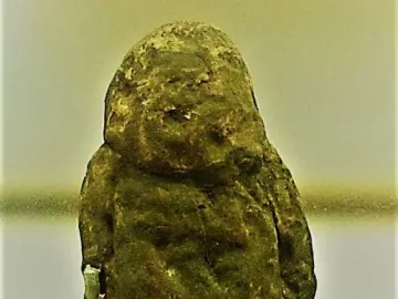 Venus of Tan-Tan stone figurine with a rough, dark greenish-brown surface and a broadly humanoid shape.