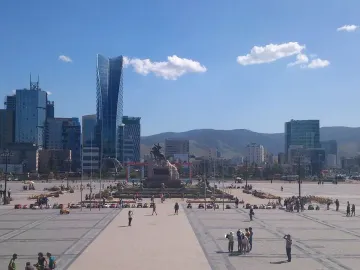 Damdin Sükhbaatar statue standing in a wide public square with pedestrians and modern buildings in the background.