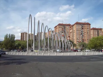Puerta de la Ilustración sculpture with shiny silver arch-like forms on a traffic island in Madrid.