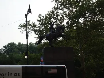 Simón Bolívar Equestrian Statue on a rearing horse, seen as a bronze silhouette against the sky and trees.