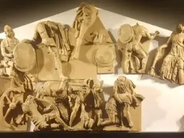 Talamone Pediment terracotta relief showing a crowded battle scene with warriors, horses, fallen figures, and a chariot rider.